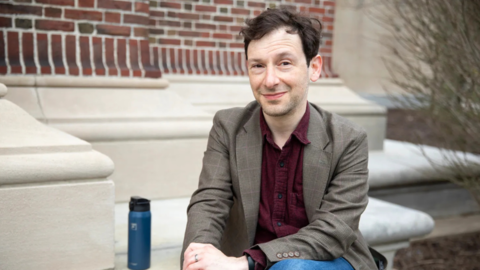 Joshua Cherniss sitting on steps smiling
