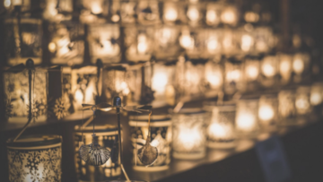 rows of prayer candles in clear glass jars on an altar